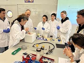 Une enseignante montre une manipulation à un groupe d'étudiants